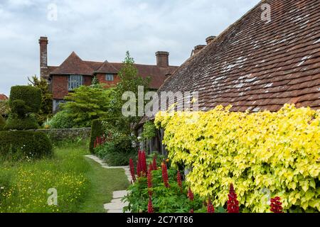 Great Dixter, East Sussex: Der Topiary Garden und der alte Kuhstall, bekannt als das "Hovel", und darüber hinaus das späte Haus von Christopher Lloyd selbst. Stockfoto