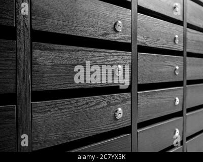 Nahaufnahme Raws von Holz unnummeriert Briefkästen und Schließfächer für Bewohner in Eigentumswohnung oder Wohnung. Moderne schöne dunkelfarbige Holz Briefkasten Panel Stockfoto