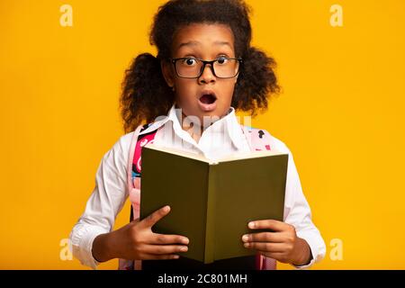 Überrascht Schulmädchen Halten Buch Blick Auf Kamera, Studio Shot Stockfoto