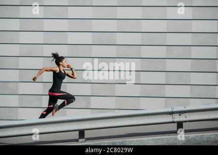 Geschwindigkeit und Lauf. Athletische afroamerikanische Mädchen in Sportkleidung, läuft auf der Straße Stockfoto