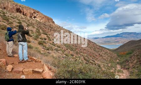 Besucher, die Fotos von Roosevelt Lake machen, nahe Upper Cliff Dwelling am Tonto National Monument, Superstition Mountains, Sonoran Desert, Arizona, USA Stockfoto