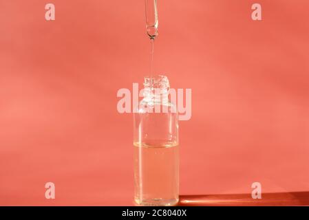 Natürliche Seren. Konzept der kosmetischen Injektion ist Hyaluronsäure, Botulinum, Serum. Kosmetische Pipette mit Tropfen kosmetischen Öls oder flüssigem Gel close-up auf einem rosa Hintergrund. Stockfoto