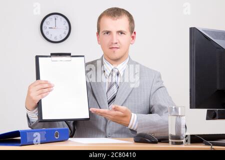 Junger Geschäftsmann, der in seinem Büro einen Vertrag vorweist Stockfoto