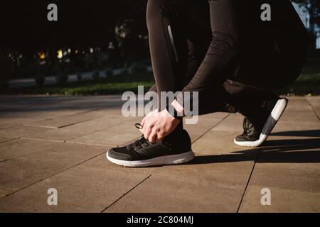 Nahaufnahme ein Mann, der beim morgendlichen Lauf im Park Schnürsenkel auf Turnschuhen bindet Stockfoto