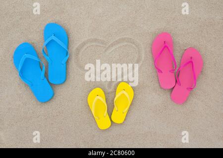 Blaue, rote, gelbe Flip Flops und Herz am Strand Stockfoto