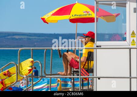 Bournemouth, Dorset, Großbritannien. Juli 2020. Wetter in Großbritannien: Heiß und sonnig, wenn die Temperaturen steigen und Sonnenanbeter zu den Stränden von Bournemouth strömen, um die Sonne und das Meer zu genießen. RNLI Lifeguard wacht an der Rettungsschwimmer-Kiosk-Hütte im Dienst. Quelle: Carolyn Jenkins/Alamy Live News Stockfoto