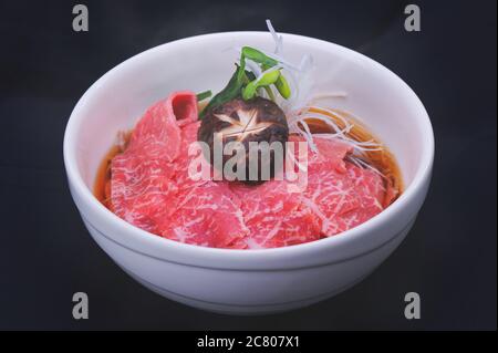 Niku Soba Rohes Rindfleisch im japanischen Stil mit Nudel und heißer Shoyu-Suppe auf dunklem Hintergrund. Stockfoto