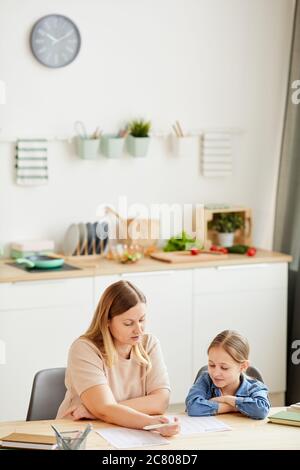 Vertikale warm-toned Porträt von fürsorgliche Mutter helfen Tochter Hausaufgaben und zu Hause studieren in gemütlichen Innenraum, kopieren Raum Stockfoto