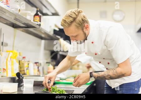 Der männliche Koch serviert köstliche Steaks auf dem Schneidebrett im Straßencafé Stockfoto