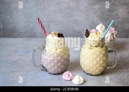 Süße Erdbeer- und Vanillemilchshakes mit Eis und Schlagsahne in Maurer-Gläsern. Stockfoto