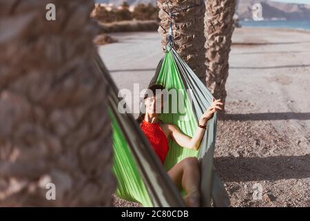 Frau liegt in Hängematte zwischen Palmen am Strand Stockfoto