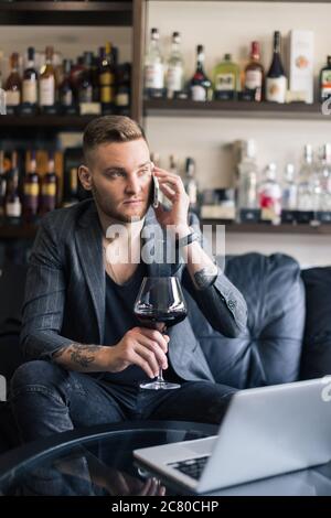 Konzept Foto von reichen Menschen Luxus Leben. Erwachsene erfolgreiche elegante Geschäftsmann tragen Anzug und Wein trinken auf dem Dach in Luxus-Penthouse Stockfoto