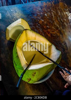 Süßes grünes Kokosnusswasser mit Trinkhalm auf dem Tisch. Tropische Kokosnussfrüchte in Koh Samui, Phangan und koh tao, surat thani und chumphon auf Bali Stockfoto