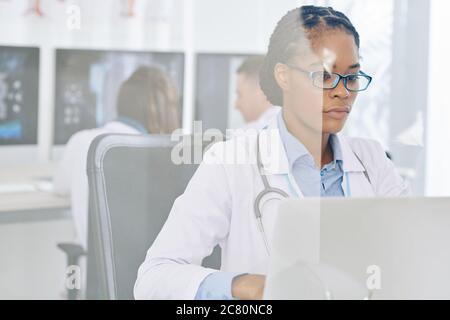Serious junge Ärztin in der Brille Überprüfung der Ergebnisse der Patienten medizinischen Tests auf Laptop Stockfoto