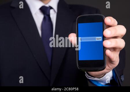 Modernes Mobiltelefon mit Suchleiste auf dem Bildschirm in Business man Hand Stockfoto