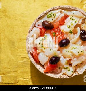 Blick in den hohen Winkel von einem Teller mit esqueixada de bacalla, ein kaltes Gericht mit Kabeljau, Tomaten, Zwiebeln und schwarzen Oliven, und mit Olivenöl, Typi gekleidet Stockfoto