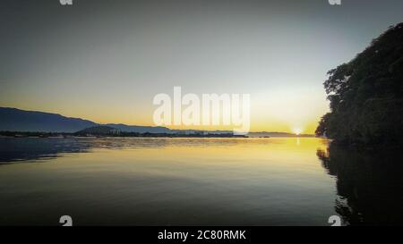 Sonnenaufgang Sonnenuntergang am Fluss 'Canal do estuário', zwischen den Städten Guaruja und Bertioga in Brasilien. Farbenfrohe und ruhige Sonnenaufgänge an einem ruhigen Fluss. Sli Stockfoto