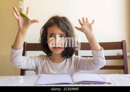 Grundschülerin macht ihre Hausaufgaben. Sie macht ihre eigenen Hausaufgaben allein zu Hause, weil die Schulen wegen der Corona pandemi geschlossen sind Stockfoto
