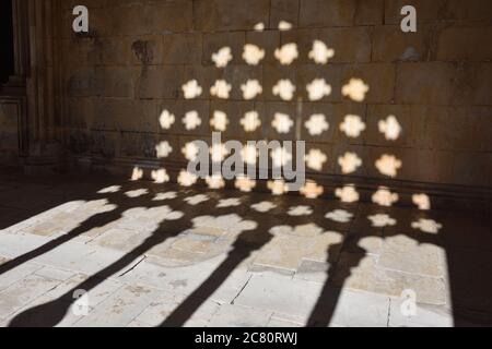 Schatten des Steins geschnitzten Fenstergrill an der Wand im Kreuzgang des Klosters von Batalha. Kloster der Heiligen Maria des Sieges. Spätgotische Archi Stockfoto