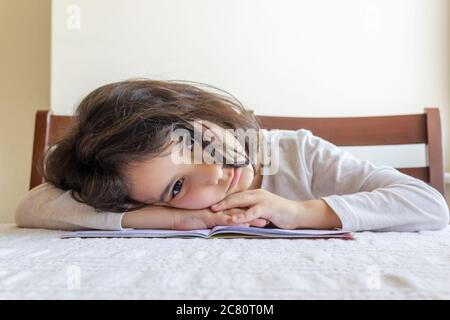 Grundschülerin macht ihre Hausaufgaben. Sie macht ihre eigenen Hausaufgaben allein zu Hause, weil die Schulen wegen der Corona pandemi geschlossen sind Stockfoto