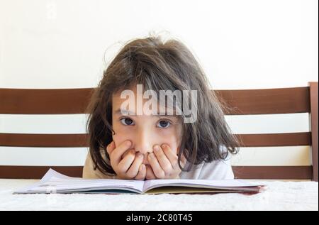 Grundschülerin macht ihre Hausaufgaben. Sie macht ihre eigenen Hausaufgaben allein zu Hause, weil die Schulen wegen der Corona pandemi geschlossen sind Stockfoto