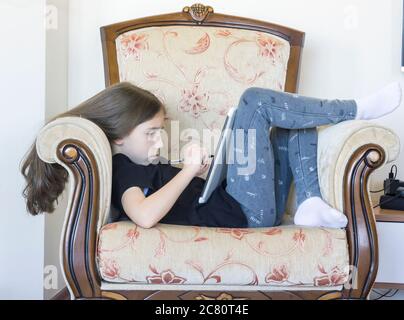 Grundschülerin macht ihre Hausaufgaben. Sie macht ihre eigenen Hausaufgaben allein zu Hause, weil die Schulen wegen der Corona pandemi geschlossen sind Stockfoto