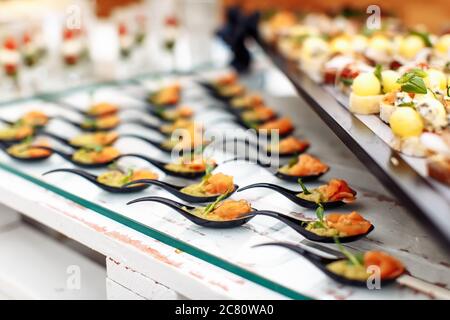 Verschiedene leichte Snacks auf Glas und Holztablett auf Hochzeitsfeier Stockfoto