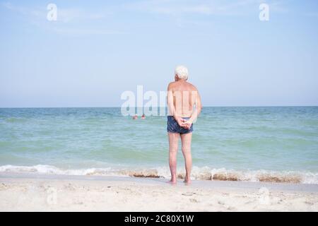 Allein unkenntlich Senior Mann stehend Meer Strand beobachten Horizont Rückansicht Traurigkeit Einsamkeit Altern Einsamkeit im Alter Stockfoto