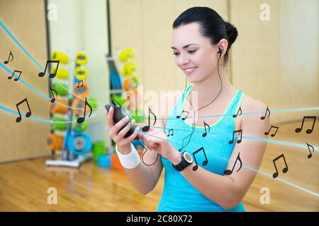 Junge schöne schlanke Frau Musik im Fitnessstudio hören Stockfoto