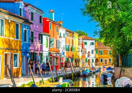 Burano, Italien, 14. September 2019: Bunte Häuser und Gebäude am Ufer des schmalen Wasserkanals mit Fischerbooten und Blick auf die Lagune von Venedig, Provinz Venedig, Region Venetien. Burano Postkarte Stockfoto