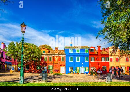 Burano, Italien, 14. September 2019: Touristen, die die Uferpromenade des engen Wasserkanals mit Fischerbooten, bunten Häusern und bunten Gebäuden entlang gehen, Provinz Venedig, Region Venetien Stockfoto