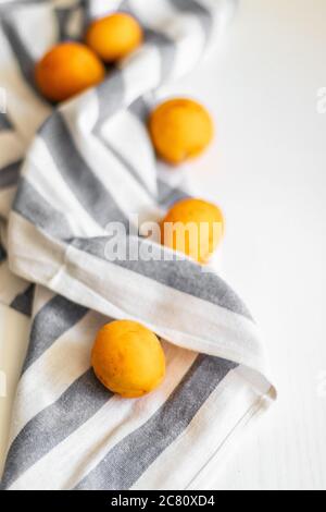 Reife frische Aprikosen mit einem gestreiften Handtuch auf weißem Hintergrund, Draufsicht, Platz für Text. Stockfoto