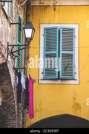 Die vertikale Aufnahme des blauen hölzernen Fensters auf dem gelben Gebäude in Itlay gefangen genommen Stockfoto