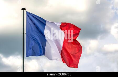 Französische Flagge winkt am späten Nachmittag in einer ruhigen Umgebung gegen einen bewölkten Himmel Stockfoto