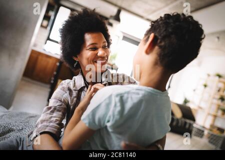 Glückliche Mutter spielen, Spaß haben, umarmen, mit ihrem Sohn zu Hause Stockfoto