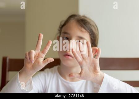 Grundschülerin macht ihre Hausaufgaben. Sie macht ihre eigenen Hausaufgaben allein zu Hause, weil die Schulen wegen der Corona pandemi geschlossen sind Stockfoto