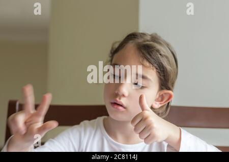Grundschülerin macht ihre Hausaufgaben. Sie macht ihre eigenen Hausaufgaben allein zu Hause, weil die Schulen wegen der Corona pandemi geschlossen sind Stockfoto