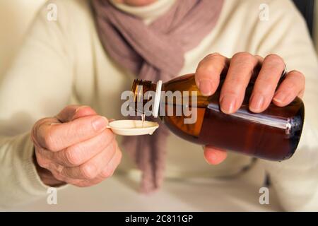 Person, die im Winter Sirup in einen Löffel gießt Stockfoto