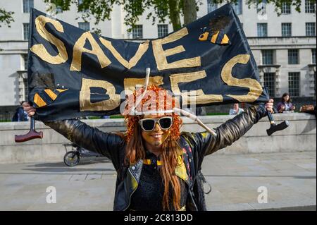 LONDON - 18. OKTOBER 2019: Der Protestierende der Extinction Rebellion hält ein Banner mit der Aufschrift Save Bees bei einem Protestmarsch der Extinction Rebellion Stockfoto