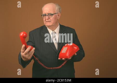 Übergewichtiger Geschäftsmann mit Brillen vor braunem Hintergrund Stockfoto