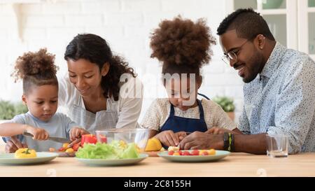 Liebevolle Biracial Eltern lehren Kinder Kochen in der Küche Stockfoto