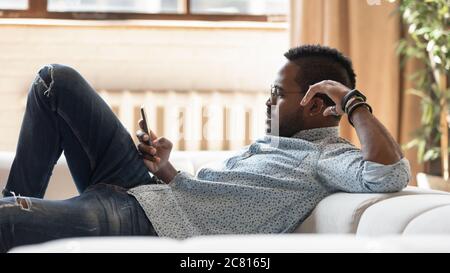 Afroamerikanischer Mann entspannen sich auf der Couch mit Handy Stockfoto