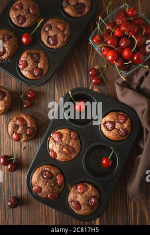 Gesunde vegane BananenkirschMuffins mit frischen Beeren auf braunem Holzhintergrund. Draufsicht. Sommeressen Stockfoto