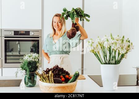 Frau, die rote Beete hält, während sie an der Küchentheke steht Stockfoto