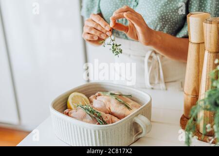 Nahaufnahme der Hände Hinzufügen aromatischer Kräuter zu rohen Wachtel Bereit zum Braten Stockfoto