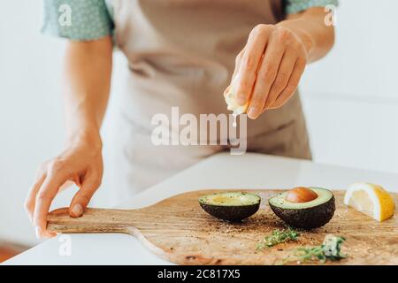 Nahaufnahme der weiblichen Hände, die Zitrone auf Avocado quetschen Stockfoto