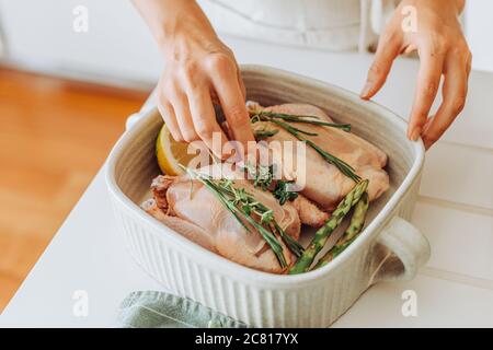 Hände, die rohe Wachtel oder Huhn mit aromatischen Kräutern vorbereiten Braten Stockfoto