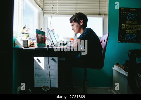 Der zehnjährige Junge arbeitet an seinem Laptop an der Heimschule Während einer Pandemie Stockfoto