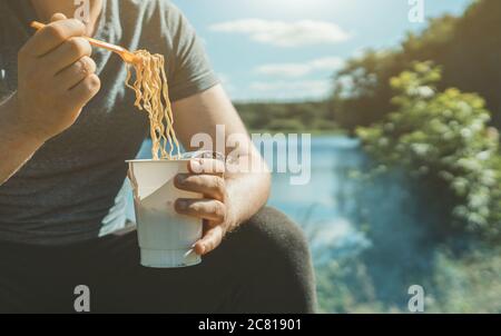 Mann mit Instant Nudeln am See. Stockfoto