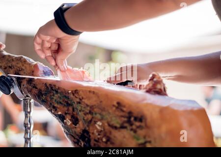 Frau schneidet iberischen Schweineschinken mit einem Schinkenhalter und Messer Stockfoto